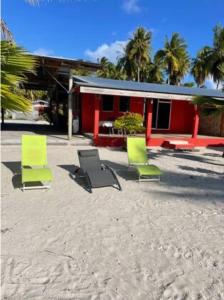 a group of chairs sitting in the sand in front of a building at Tikehau HereArii Airbnb in Tikehau