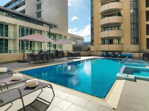 een groot zwembad met stoelen en een gebouw bij 2 Bed 2 Bath Apartment in Braddon, Canberra - Pool, Gym and Free Parking in Canberra