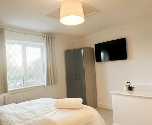 a bedroom with a bed and a cabinet with a television at Vista Lodge in Wythenshawe