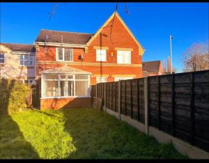 una casa di mattoni con una recinzione di fronte di Vista Lodge a Wythenshawe