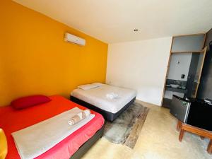2 camas en una habitación con paredes de color naranja en Casa Coral Mahahual - Costa Maya en Mahahual