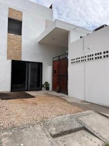 a white house with a large door and a driveway at Casa Coral Pueblito - Self Check In in Mahahual