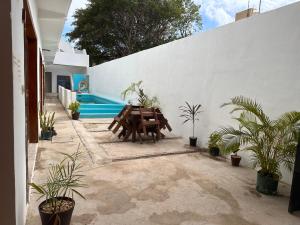 a patio with a table and potted plants next to a wall at Casa Coral Pueblito - Self Check In in Mahahual