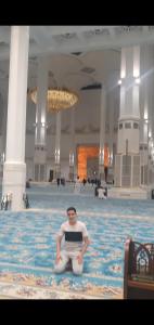 a man sitting on a rug in a large building at Les 2 palmiers in Kouba