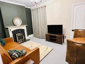 a living room with a fireplace and a television at The Naunton Nook in Cheltenham