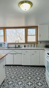 a kitchen with white cabinets and a black and white tile floor at Tranquil Coastal Escape in Port Stanley