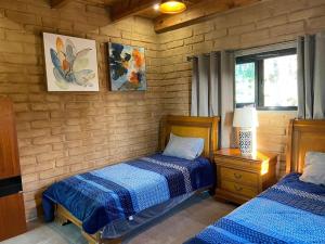 a bedroom with two beds and a lamp on a night stand at LAS ESTRELLAS CABAÑAS EN EL BOSQUE ARTEAGA COAHUILA mex in Los Lirios