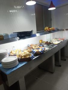 a buffet line with plates and bowls of food at Hotel Monte Belo Palace in Aparecida