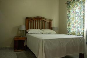 a bedroom with a bed with white sheets and a window at DEMAROYS in Treasure Beach