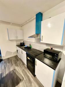 a kitchen with white cabinets and a black microwave at Cosy 3 Bed Apartment,Free Parking in Birmingham in Birmingham