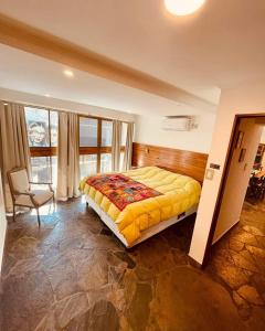 - une chambre avec un lit et une chaise dans l'établissement Peatonal Suites Paraná, à Paraná