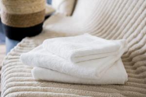 a stack of white towels on a bed at Sweet Home 10min from DisneyLand Paris and 25min from Paris in Bussy-Saint-Georges