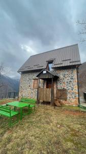 ein Gebäude mit zwei grünen Bänken davor in der Unterkunft Lindja e Diellit in Bulqizë