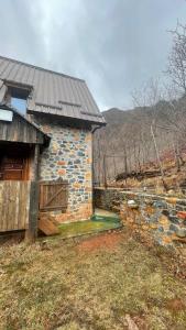 ein Steingebäude mit einer Holztür und einer Steinmauer in der Unterkunft Lindja e Diellit in Bulqizë