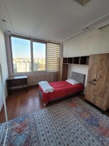 um quarto com uma cama vermelha e uma grande janela em Journey's Ease em Istambul