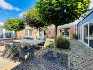 a patio with a table and chairs under a tree at House Xxl Free Parking 3 Bedrooms in Tilburg