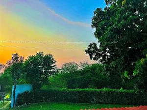 um pôr-do-sol sobre um quintal com árvores e uma cerca em Hotel Pallara Campestre em Ricaurte