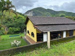 a yellow house with a table and a bench at Casa no campo in Bom Jardim