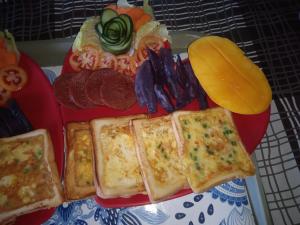 a red plate of food with sandwiches and other foods at Sarah's Garden BnB & Spa in Clarin