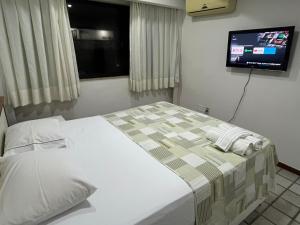 ヴィラ・ヴェーリャにあるFlats beira mar - praia da costaの壁にテレビが付いたベッドのある寝室