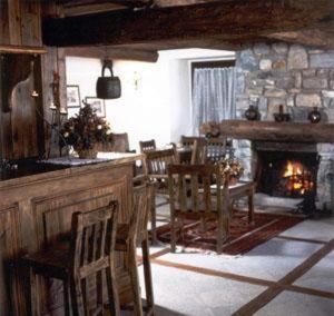 a living room with a fireplace and a table and chairs at Hotel Tavernier in Courmayeur