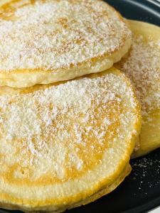 two pancakes with powdered sugar on a black plate at Bintana Sa Paraiso in Mambajao