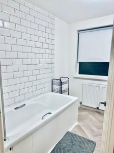 La salle de bains est pourvue d'une baignoire blanche et d'une fenêtre. dans l'établissement *Newcastle City* Modern 2 Bedroom House, à Newcastle upon Tyne