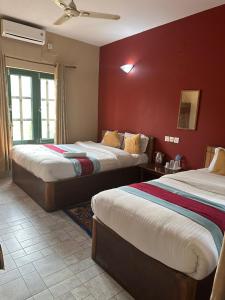 2 camas en una habitación con paredes rojas en Wild Horizons Guest House, en Sauraha