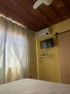a bedroom with a bed and a window with a tv at Flat Maricá com ar-condicionado in Maricá