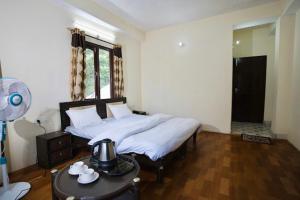 a bedroom with a bed and a table with a fan at The Regency by Boho Stays in Shimla