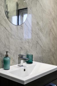 a bathroom sink with a mirror and a soap dispenser at Manchester Serviced Accommodation NorthernNightzzz - The Park in Manchester +45 photos