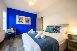 een blauwe slaapkamer met een bed met handdoeken erop bij Manchester Serviced Accommodation NorthernNightzzz - The Park in Manchester