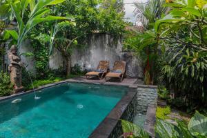 a swimming pool with two chairs and a waterfall at Sari Bamboo Villas in Ubud
