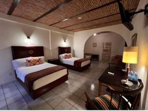 Jalostotitlán的住宿－Hotel & Eventos Xalos，酒店客房设有两张床、一张桌子和一张书桌。
