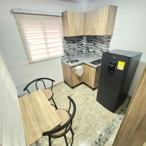 una pequeña cocina con nevera negra y sillas en Apartamentos todos con aire acondicionado, en Ibagué