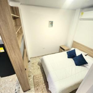 a bedroom with a white bed and blue pillows at Apartamentos todos con aire acondicionado in Ibagué