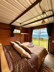 a bedroom with a large bed with a large window at Refugio Aventura, romántico glamping montañero in Tabio