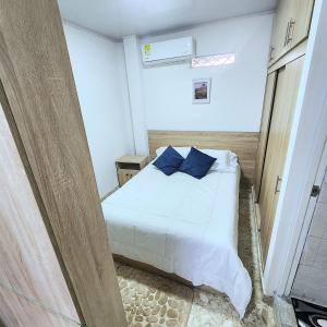 1 dormitorio con cama blanca y almohadas azules en Apartamentos todos con aire acondicionado, en Ibagué