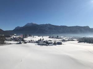 a snowy field with a town and mountains in the background at Haus Mayerbüchler - Chiemgau Karte in Inzell