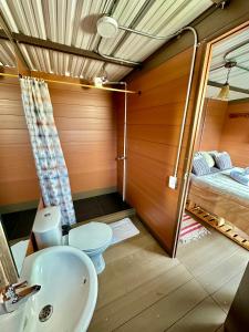 1 cama y baño con lavabo y aseo. en Refugio Aventura, romántico glamping montañero, en Tabio