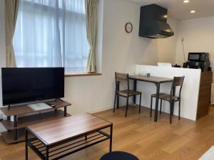 een woonkamer met een televisie en een tafel met stoelen bij GEビルAFUSO in Atsutabaru