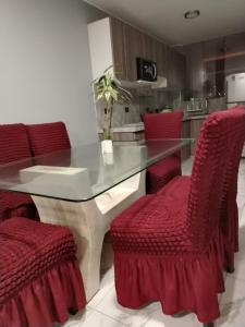 comedor con mesa de cristal y sillas rojas en Departamento moderno en el centro de la ciudad, en Ilo