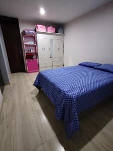 1 dormitorio con 1 cama con manta azul a cuadros en Departamento moderno en el centro de la ciudad, en Ilo