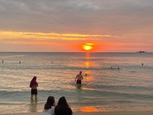 people standing in the water at the beach at sunset at Beach Hotel Grand World (La La Homestay) in Phú Quốc