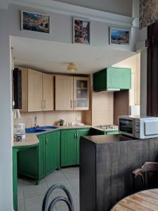 a kitchen with green cabinets and a microwave at 9 Doors in Tbilisi City