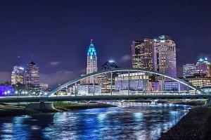 a bridge over a river with a city at night at The Troubadour- Location Location in Columbus
