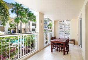 a balcony with a wooden table and chairs and windows at Laguna on Hastings, Apartment 117, Noosa Heads in Noosa Heads
