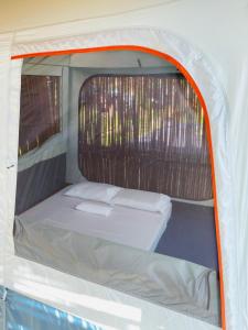 - un petit lit à l'arrière d'une tente blanche dans l'établissement Russell Place Tent, à Port Barton