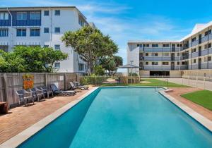 a swimming pool with chairs and a building at Ultimate Coastal Escape + Amazing Views in Caloundra