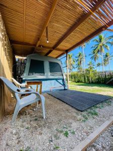 a parked camper under a wooden roof with a chair at Russell Place Tent in Port Barton